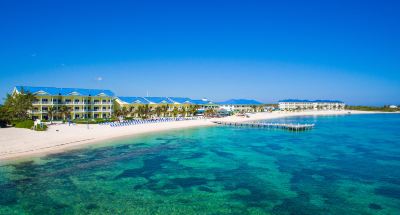 a beautiful beach with clear blue water , white sand , and palm trees under a clear sky at Wyndham Reef Resort Grand Cayman