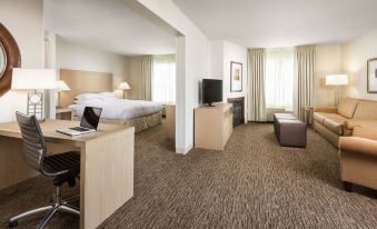 a modern hotel room with a bed , desk , and couch , as well as a bedroom area with a bed , desk , and couch at DoubleTree by Hilton Portland - Tigard