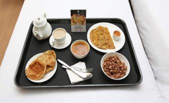 a tray filled with a variety of breakfast items , including pancakes , eggs , and coffee , is placed on a bed at The Horizon