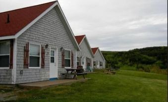 a row of small , red - roofed houses with picnic tables and umbrellas in front of them at Chisholms of Troy Coastal Cottages