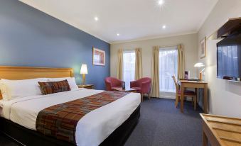 a hotel room with a blue and white bed , a desk , two chairs , and a window at Econo Lodge Karratha