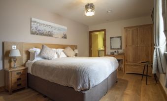 a large bed with white sheets and a gray headboard is in a room with wooden floors at Crossways Inn