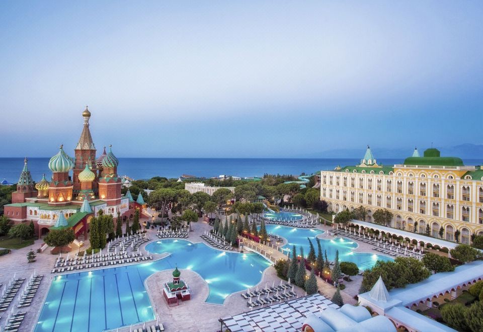 a large resort with multiple swimming pools , palm trees , and a castle - like building overlooking the ocean at Kremlin Palace