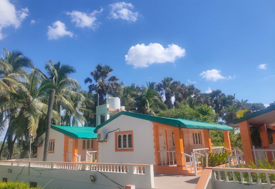 a tropical house with an orange and white exterior is surrounded by palm trees under a blue sky at Hotel Palms