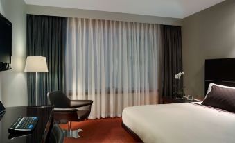 a hotel room with a comfortable bed , curtains , and a black chair near the window at Park Plaza Westminster Bridge London