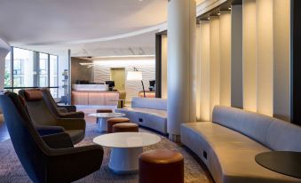 a modern hotel lobby with comfortable seating , a reception desk , and a large column in the center at Washington Dulles Airport Marriott