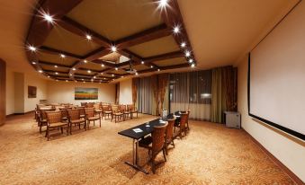 a large , empty conference room with wooden floors , multiple tables , and chairs arranged for meetings at Hotel Majestic