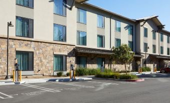 a person is walking in front of a hotel building with a parking lot in the foreground at Courtyard Thousand Oaks Agoura Hills