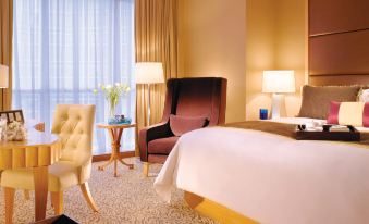 a hotel room with a king - sized bed , two nightstands , a chair , and a chair in the corner at Oakwood Premier Cozmo Jakarta