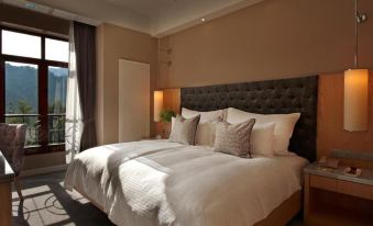 a large bed with white linens and a brown headboard is in a room with a window at The Chateau Spa & Wellness Resort