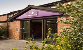 a building with a purple sign above the entrance and bushes in front of it at Premier Inn Crewe (Nantwich)