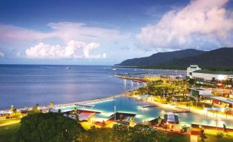 a resort with a large pool surrounded by trees and a body of water in the background at Cairns Sunland Leisure Park