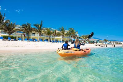 a group of people , including a man and a woman , are kayaking in the ocean near a beach at Wyndham Reef Resort Grand Cayman