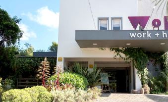 "a white building with a sign that reads "" wexcom "" on it , surrounded by greenery and plants" at Work Hotel