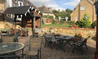 an outdoor patio with a variety of tables and chairs , surrounded by a brick wall at Parrett Hotel