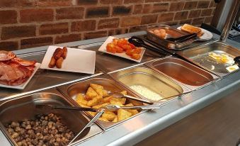 a buffet table filled with a variety of food items , including hot dogs , fries , and other snacks at The Atherstone Red Lion Hotel