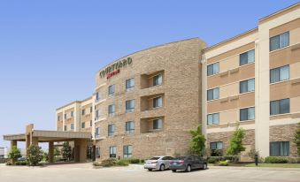 a large hotel building with a parking lot in front of it , where several cars are parked at Courtyard Lufkin