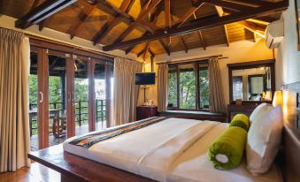 a large bed with a green pillow is in a room with wooden floors and walls at Horison Green Forest Bandung