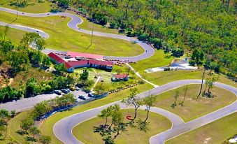 an aerial view of a winding road with a building in the background and trees on either side at Mareeba Motor Inn