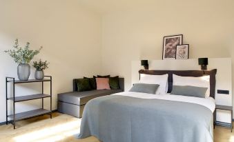 a bedroom with a bed , couch , and bookshelves , featuring blue bedding and a potted plant at Hotel Maribor & Garden Rooms