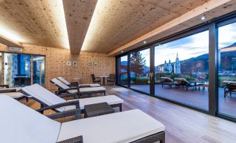 a modern , wooden - walled room with multiple lounge chairs and large windows offering views of the surrounding landscape at Hotel Grüner Baum