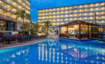 a hotel with a large outdoor pool surrounded by lounge chairs and umbrellas , as well as a restaurant nearby at Sol Costa Daurada