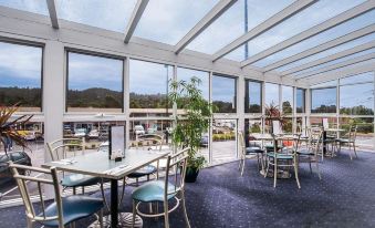 a restaurant with white walls , glass walls , and blue carpet , offering a view of the outside at Kingston Hotel Motel