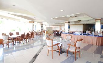 a large dining room with several tables and chairs arranged for a group of people to enjoy a meal together at Grand Elty Singgasana Tenggarong