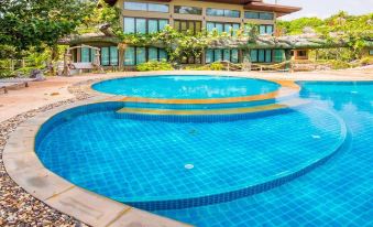 a large swimming pool with a water feature in the middle , surrounded by a house and trees at Blues River Resort