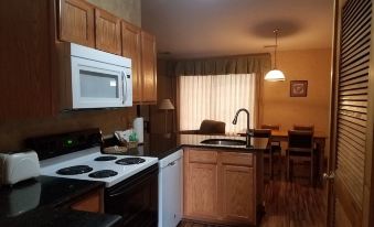 a kitchen with wooden cabinets , a white microwave oven , and a dining table in the background at Creekside Village