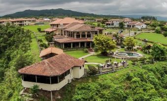 a large , two - story house with a red tile roof is surrounded by lush greenery and trees at Hacienda Los Molinos Boutique Hotel & Villas