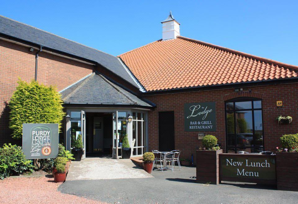 "a brick building with a large red tile roof and a sign that reads "" new lease mercies "" on it" at Purdy Lodge