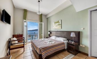 a bedroom with a bed , nightstand , and chairs is shown with a view of the ocean at Golden View