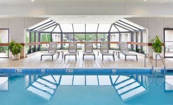 an indoor swimming pool surrounded by chairs and tables , providing a relaxing atmosphere for guests at Courtyard Rochester Brighton