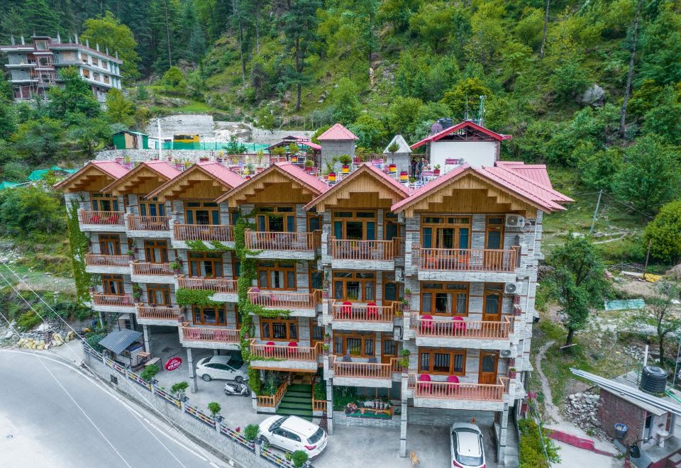 a large wooden building with a red roof and balconies is situated in a mountainous area at Hotel Royal Palace