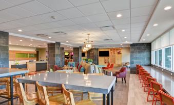 a modern , spacious restaurant with multiple dining tables and chairs , as well as a bar area at Home2 Suites by Hilton la Porte