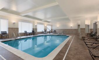 an indoor swimming pool surrounded by windows , with lounge chairs placed around the pool area at Hilton Garden Inn Falls Church