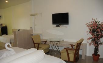 a modern hotel room with a bed , dining table , and chairs , as well as a flat screen tv mounted on the wall at Saraburi Garden Resort