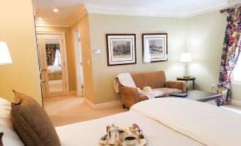 a bedroom with a bed , two chairs , and a tray on the bed , as well as a chair in the room at Copper Beech Inn