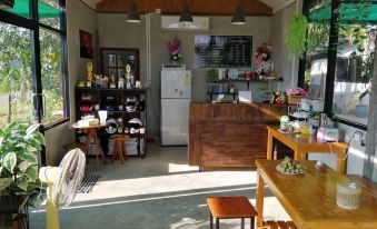 a kitchen with wooden tables and chairs , a refrigerator , and various appliances in the background at Piamsuk Resort