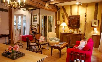 a cozy living room with wooden beams , red couches , and a dining table , surrounded by other furniture at Ombre Rose