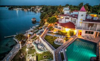 a large house with a red roof is situated on the shore of a lake at Hotel Laguna Bacalar