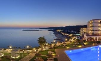 a luxurious resort with a pool and ocean view at dusk , illuminated by lights on the buildings at Villa Le Blanc Gran Melia