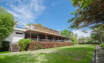 a large , modern building surrounded by lush greenery and grass , with a blue sky overhead at Almont Beach Resort