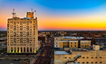 a city street at dusk , with a tall building in the background and a colorful sky overhead at Hilton Garden Inn Flint Downtown