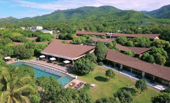 aerial view of a resort surrounded by trees and mountains , with a pool visible in the foreground at Astoria Palawan