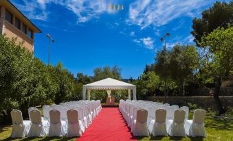 a wedding ceremony taking place in a grassy field , with rows of chairs set up for guests at Mon Port Hotel & Spa