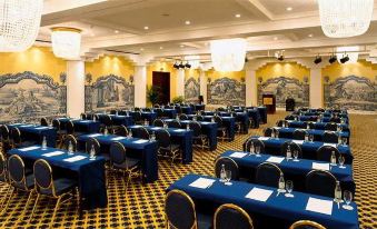 a large conference room with rows of blue tables and chairs , blue tablecloths , and a chandelier at Vila Vita Parc