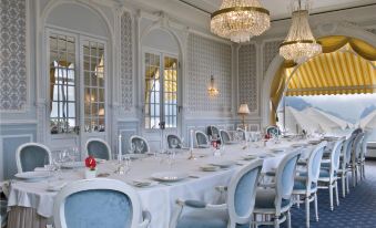 a large dining room with a long white table and blue chairs , surrounded by chandeliers and elegant decorations at Le Mirador Resort and Spa