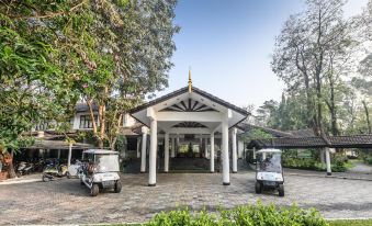 a white building with a thatched roof , surrounded by trees and two golf carts parked in front at Supalai Pasak Resort Hotel and Spa